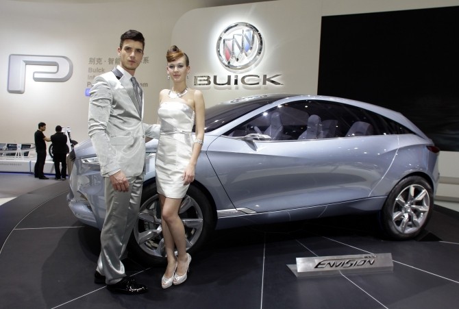 Models stand next to the Buick Envision SUV concept car at Auto China 2012 in Beijing