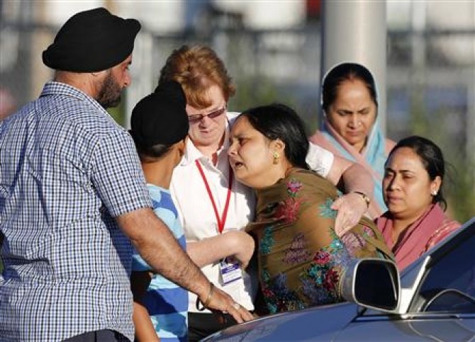 A distraught women is helped to a car outside of the Sikh temple in Oak Creek, Wisconsin