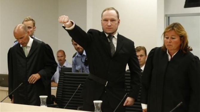 Norwegian mass killer Breivik gestures as he arrives in the court room at Oslo Courthouse