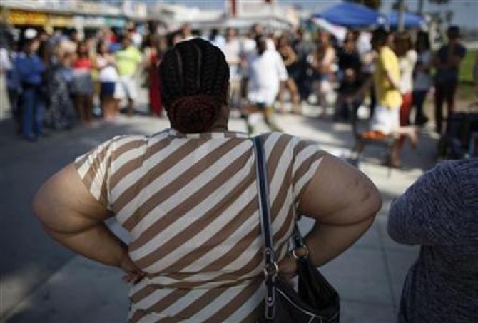 An overweight woman watches a street performer at Venice Beach in Los Angeles