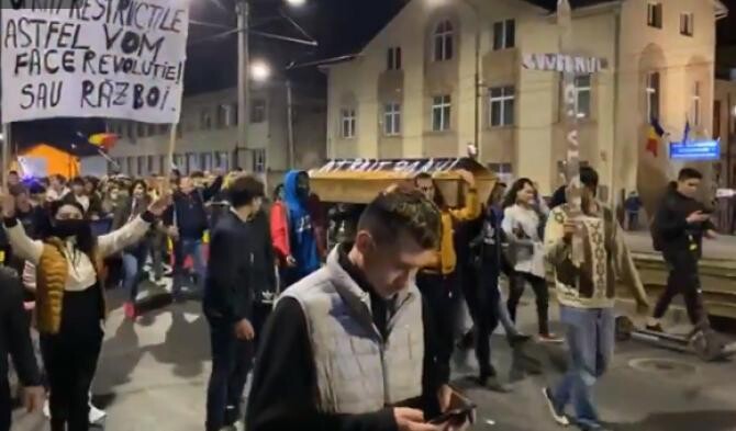 Protestatarii din Arad mărșăluiesc pe străzi cu un sicriu și cu o cruce pe care scrie 'Guvernul' - Captură Video Timișoara Știri Facebook