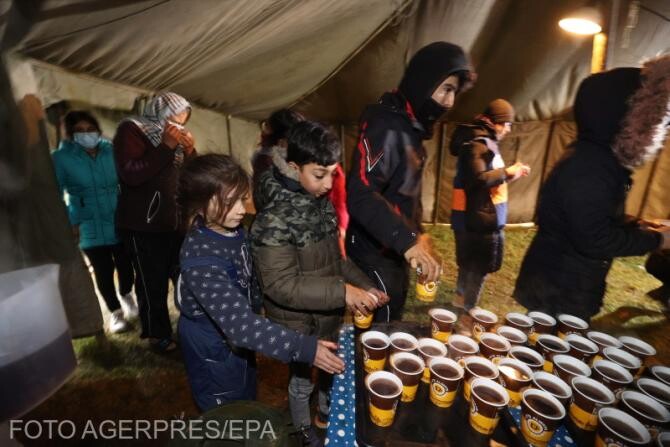 Migranții primesc ceai în tabăra din apropierea punctului de trecere Bruzgi
