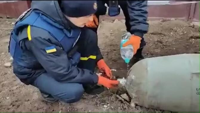 Doi pirotehniști din Ucraina dezamorsează o bombă cu mâinile, folosind doar o sticlă mică de apă / Foto: Captură video   Epoch Times - România 