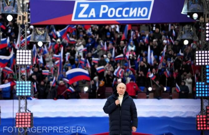 Președintele rus Vladimir Putin, în timpul discursului de pe stadionul din Moscova pentru susținerea războiului împotriva Ucrainei. În spate, pe scenă, mesajul „Pentru Rusia!”